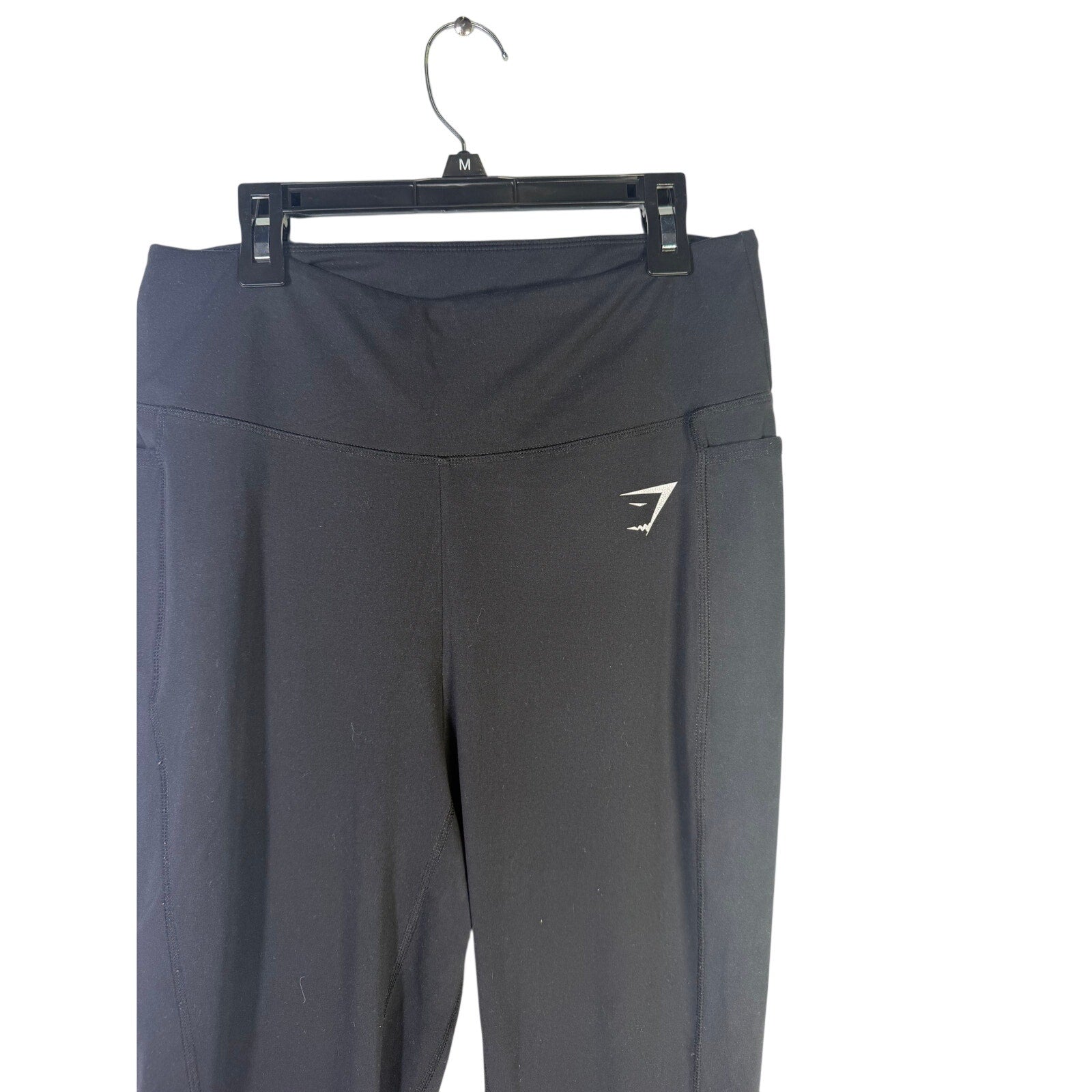 Black Gymshark women’s high-waisted side pocket leggings, size L, shown on a person with a close-up of the fitted athletic wear.