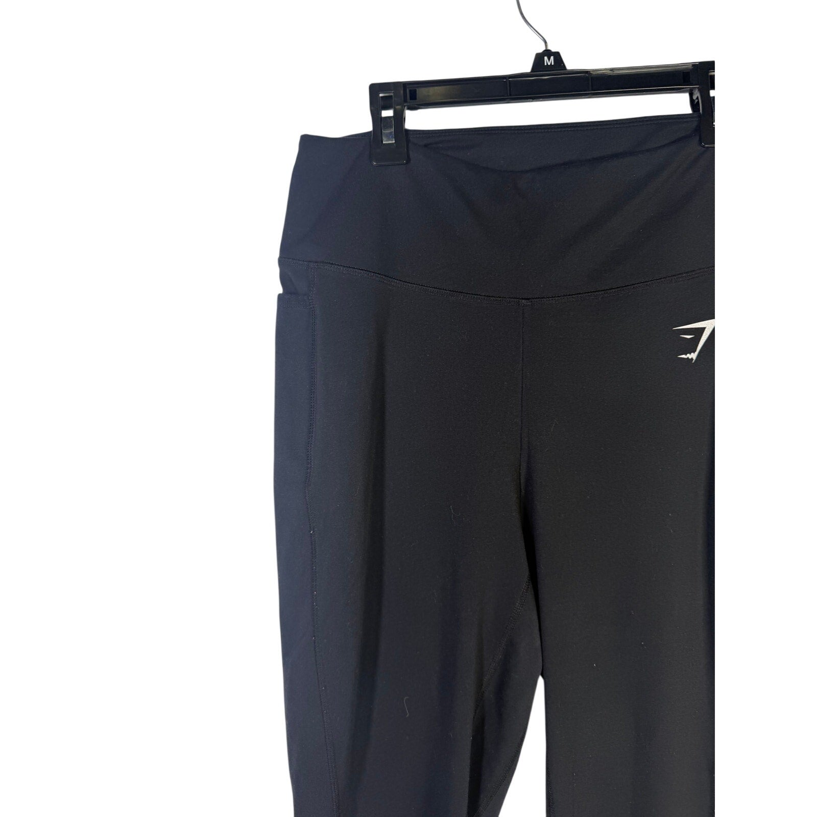 Black Gymshark women’s high-waisted side pocket leggings laid flat showing the stretchy fabric and side pocket design.
